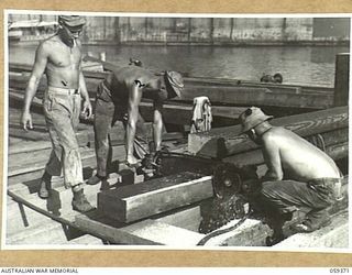 LAE, NEW GUINEA, 1943-11-05. ENGINEERS OF THE DETACHMENT OF HEADQUARTERS, 1052ND ENGINEERS PORT CONSTRUCTION AND REPAIR GROUP, UNITED STATES ARMY, WORKING ON THE CONSTRUCTION OF THE FIRST LIBERTY ..