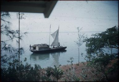 A house-boat, with a sail, is passing along : Port Moresby, Papua New Guinea, 1953 / Terence and Margaret Spencer