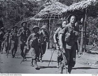 PAPUA, NEW GUINEA, 1942-10. MEN OF THE 2/33RD AUSTRALIAN INFANTRY BATTALION MARCHING THROUGH THE SMALL NATIVE VILLAGE OF NAURO ON THEIR WAY THROUGH THE OWEN STANLEY RANGES TO KOKODA. NOTE EACH MAN ..