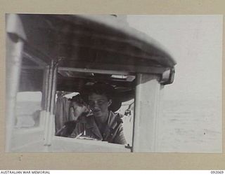 SALAMAUA - LAE, NEW GUINEA. 1945-05-19. CORPORAL G.M. BENNETT (1), AT THE WHEEL OF THE LAUNCH ON THE WAY BACK FROM SALAMAUA. A LAUNCH TRIP TO THE ISLAND, FROM LAE, WAS ORGANISED FOR THE AUSTRALIAN ..