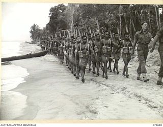 BOUGAINVILLE ISLAND. 1945-01-25. PERSONNEL OF "A" COMPANY, 1ST NEW GUINEA INFANTRY BATTALION LED BY NX136561 SERGEANT J.S. BLAIR (1), MARCHING ALONG THE BEACH DURING THEIR REFRESHER TRAINING COURSE
