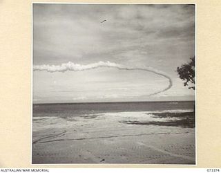 PORT MORESBY, NEW GUINEA. 1944-05-23. AN INTERESTING EFFECT CREATED BY AN AIRCRFT TRAILING A SMOKE SCREEN ABOVE THE BAY