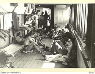 AT SEA, 1944-03. TROOPS PLAYING "HOUSIE" BESIDE DECK BUNKS ON A SECTION OF THE STARBOARD SIDE ABOARD HT TAROONA. THIS TROOPSHIP IS CARRYING SERVICEMEN OF THE THREE AUSTRALIAN SERVICES, AND AMERICAN ..