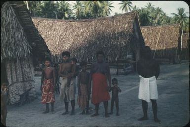 Man with women and children stading in front of village houses : Tasman Islands, Papua New Guinea, 1960 / Terence and Margaret Spencer