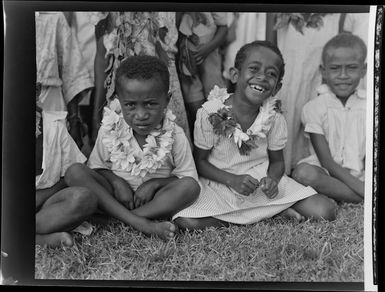 Young boy and girl sitting with a group, meke, Vuda village, Fiji