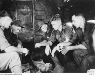1944-03-23. NEW GUINEA. FIVE MEMBERS OF THE AUSTRALIAN TROOPS WHO HELPED TO MAKE THE DEPARTMENT OF INFORMATION FILM "JUNGLE PATROL" ENJOY A CARD GAME OF FIVE HUNDRED WHILE TRAVELLING IN THE ..