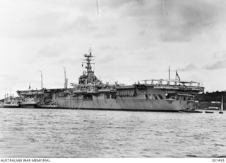 MANUS ISLAND, NEW GUINEA. 1949-09. PORT QUARTER VIEW OF THE AIRCRAFT CARRIER HMAS SYDNEY (III) AT ANCHOR. NOTE THE TYPE 960 AIR SEARCH RADAR AT THE MASTHEAD, TYPE 293Q AIR/SURFACE SEARCH RADAR JUST ..