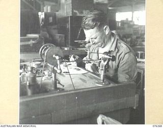 LAE, NEW GUINEA. 1944-09-27. AN INSTRUMENT MAKER OPERATING A WATCHMAKERS LATHE IN THE WORKSHOP OF THE 43RD FIELD ORDNANCE DEPOT