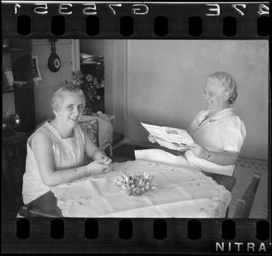 Mrs Barron [probably in her home?] and [sister?] reading a Whites Aviation magazine, Rarotonga, Cook Islands