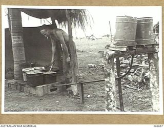 RAMU VALLEY, NEW GUINEA. 1943-12-21. QX13820 PRIVATE E. LIGHTBODY, COOK, HEADQUARTERS, ROYAL AUSTRALIAN ENGINEERS, 7TH AUSTRALIAN DIVISION OPERATING AN OIL AND WATER DRIP CONSTRUCTED FROM EMPTY 25 ..