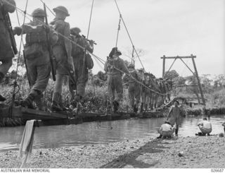 MILNE BAY, PAPUA. 1942-10. AUSTRALIAN INFANTRY CROSSING A RIVER IN THE MILNE BAY AREA BY MEANS OF A SUSPENSION BRIDGE CONSTRUCTED BY THE 2/4TH FIELD COMPANY, ROYAL AUSTRALIAN ENGINEERS