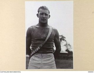 HERBERTON, QLD. 1945-01-19. PRIVATE CREBAR, 2/17 INFANTRY BATTALION, WEARING THE BLUE SASH AWARDED FOR GAINING 1ST PLACE IN THE 440 YARDS RACE. THE MEN ARE PARTICIPATING IN THE 9 DIVISION GYMKHANA ..