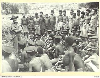 KARKAR ISLAND, NEW GUINEA. 1944-06-04. LULUAIS (CHIEFS), VILLAGE TULTULS, (CHIEF'S ASSISTANTS), AND VILLAGE MEDICAL TULTULS (ORDERLIES) BEING ADDRESSED BY PX150 CAPTAIN R.H. BOYAN, AUSTRALIAN NEW ..