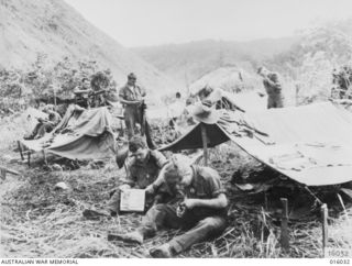 NEW GUINEA. UPPER RAMU VALLEY ADVANCE. 1 NOVEMBER 1943. FROM THEIR OBSERVATION POST CPL. C. BRINE OF PORT PIRIE, SOUTH AUSTRALIA AND PTE. D. BLACKER OF CUMMINS, SOUTH AUSTRALIA LOOK ALONG THE URIA ..