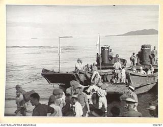 SORAKEN, BOUGAINVILLE, 1945-09-17. MEMBERS OF 8 INFANTRY BATTALION WATCHING A JAPANESE WORKING PARTY LOADING RATIONS ONTO JAPANESE BARGES FOR TRANSPORT AND DISTRIBUTION TO JAPANESE TROOPS IN THE ..