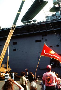 A U.S. Marine Corps flag represents the Marines aboard the amphibious assault ship USS GUAM (LPH-9) as the vessel departs for the Persian Gulf in response to Iraq's invasion of Kuwait