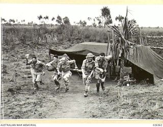 NEW GUINEA. 1942-08-03. FROM THEIR "BEDOUIN" - LIKE TENTS IN NEW GUINEA, THESE A.I.F. ANTI-AIRCRAFT GUNNERS RUSH OUT TO THEIR POSTS WHEN THE AIR RAID ALARM SOUNDS