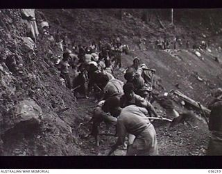 REINHOLD HIGHWAY, NEW GUINEA. 1943-08-23. NATIVES ENGAGED ON WIDENING THE HIGHWAY BETWEEN FOX'S SADDLE AND THE CENTRE CAMP