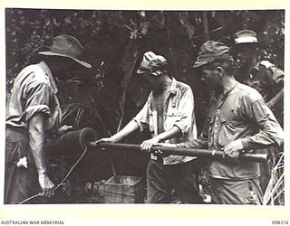 PUT PUT, NEW BRITAIN. 1945-10-20. SAPPER MCDONALD, 13 FIELD PARK COMPANY, SUPERVISING THE RAMMING OF GELIGNITE INTO THE BARRELS OF A JAPANESE NAVAL GUN DURING ITS DESTRUCTION BY JAPANESE SOLDIERS