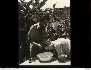 NADZAB, NEW GUINEA. C. 1944. 501298 SISTER NAN REID WASHES THE HAIR OF 500343 SENIOR SISTER NAN MCBEAN OF SYDNEY, NSW, OVER A BOWL OF WATER. BOTH ARE MEMBERS OF THE RAAF NURSING SERVICE ATTACHED TO ..