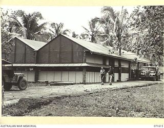 LAE, NEW GUINEA. 1944-03-24. V161015 CRAFTSMAN G. A. WALKER (LEFT), PICTURED WITH SERGEANT BERMAN (RIGHT), OUTSIDE THE INSTRUMENT AND ELECTRICAL REPAIR BUILDING AT THE AUSTRALIAN FORTRESS WORKSHOP