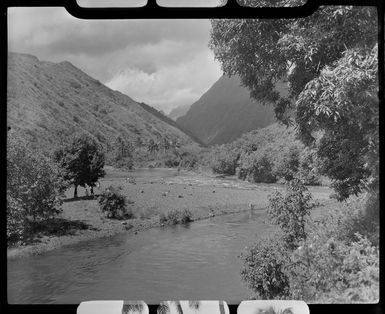 River scene, Tahiti, showing trees, hills and people at the river