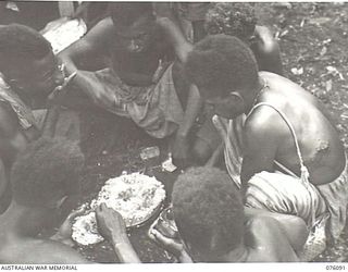 KARKAR ISLAND, NEW GUINEA. 1944-09-19. NATIVES EATING RICE BEFORE MOVING TO WORK AT PLANTATIONS UNDER THE DIRECTION OF THE AUSTRALIAN NEW GUINEA ADMINISTRATIVE UNIT