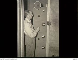 MADANG, NEW GUINEA. C. 1944-10. 265584 FLIGHT LIEUTENANT J. E. PARRIS, PARKES, NSW, CONTROLLING THE TRANSMISSION OF RAAF RADIO "THE VOICE OF THE ISLANDS". THE TRANSMITTER HAS A 250 WATTS OUTPUT AND ..