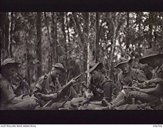 SALAMAUA AREA, NEW GUINEA. 1943-07-23. AUSTRALIAN AND AMERICAN TROOPS CHECKING THEIR WEAPONS BEFORE GOING INTO ACTION. AMERICAN TROOPS WERE ATTACHED TO AUSTRALIAN UNITS IN ORDER TO GAIN EXPERIENCE ..