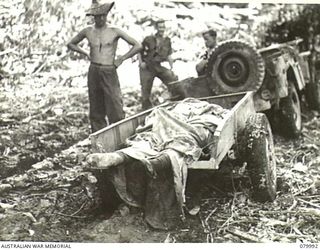 BOUGAINVILLE, SOLOMON ISLANDS. 1945-03-28. THE BODY OF A JAPANESE SOLDIER BEING REMOVED BY JEEP TRAILER FROM THE VICINITY OF THE 5TH BATTERY, 2ND FIELD REGIMENT, ROYAL AUSTRALIAN ARTILLERY AFTER ..