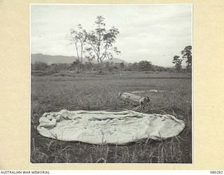 NADZAB, NEW GUINEA. 1944-10-21. A 12 FOOT HESSION PARACHUTE IN TESTS AT HEADQUARTERS NEW GUINEA FORCE. THE PARACHUTE, USED WITH STORPEDO CONTAINERS TO LESSEN IMPACT, IS DROPPED AT 3 TIMES THE SPEED ..