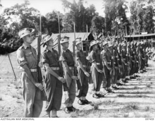 TOROKINA, BOUGAINVILLE. 1945-10-03. THE GUARD OF HONOUR FROM 7 INFANTRY BRIGADE, HEADQUARTERS 3 DIVISION, PRESENT ARMS DURING THE BLESSING OF THE CONGREGATION BY DR WADE, OF USA, BISHOP OF THE ..