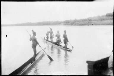 One person standing and paddling in a canoe and four people standing and paddling in a second canoe, Ramu River, New Guinea, 1935, 2 / Sarah Chinnery