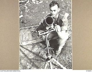 1943-09-14. NEW GUINEA. KOMIATUM RIDGE. PTE. STAN ELVY OF PERTH, W.A., WITH A THREE INCH MORTAR ABANDONED BY THE JAPANESE AT KOMIATUM RIDGE. THE MORTAR WAS OF A DUTCH MANUFACTURE AND IT HAD ..