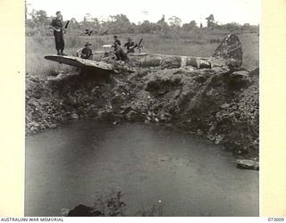 MADANG, NEW GUINEA. 1944-04-26. AUSTRALIAN TROOPS EXAMINE THE REMAINS OF A JAPANESE NAKAJIMA KI-43 OSCAR AIRCRAFT. THE AIRCRAFT IS ONE OF MANY JAPANESE FIGHTERS WHICH LITTER THE NEWLY CAPTURED ..