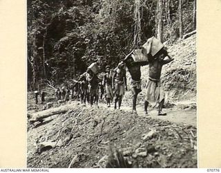 WAMPIT, NEW GUINEA. 1944-03-02. PAPUAN NATIVE BOYS ABOUT 70 MILES FROM WAU ON THE WAU - LAE ROAD. THEY ARE CARRYING STORES FOR HEADQUARTERS, COMMANDER ROYAL ENGINEERS (A.I.F.), FROM JEEPS THAT WERE ..