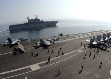 U.S. Navy Sailors and numerous F/A-18 Hornet aircraft are seen on the flight deck of the Nimitz Class Aircraft Carrier USS DWIGHT D. EISENHOWER (CVN 69) while the Tarawa Class Amphibious Assault Ship USS SAIPAN (LHA 2), (back), navigates alongside the carrier in the Arabian Sea on Nov. 20, 2006. Both ships are currently conducting maritime security operations in the region. (U.S. Navy photo by Mass Communication SPECIALIST SEAMAN David Danals) (Released)