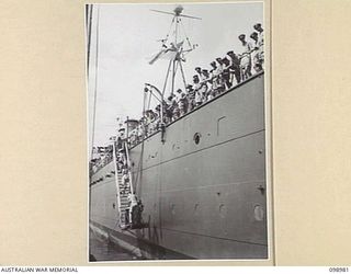 WEWAK HARBOUR, NEW GUINEA. 1945-11-25. TROOPS OF 6 DIVISION EMBARK ON HMAS SHROPSHIRE FOR RETURN TO AUSTRALIA FOR DISCHARGE. SHOWN, THE GANGWAY BEING RAISED AFTER ALL TROOPS ARE ABOARD