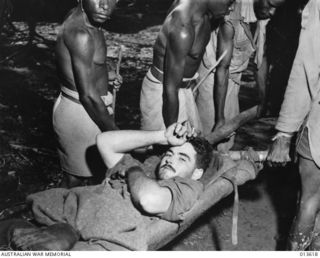 1942-11-23. NEW GUINEA. OIVI. CPL. R.D. SOMERVILLE (QUEENSLAND) BEING TAKEN FROM A DRESSING STATION JUST AFTER THE FIGHTING AT OIVI. (NEGATIVE BY G. SILK)