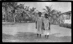 Two women on a lawn outside a building