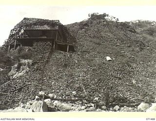 PORT MORESBY, PAPUA, NEW GUINEA. 1944-03-27. THE CAMOUFLAGED COMMAND POST AT PAGA BATTERY, COAST ARTILLERY VIEWED FROM THE BEACH. THE BATTERY, EQUIPPED WITH A SEARCHLIGHT AND TWO SIX INCH GUNS ..
