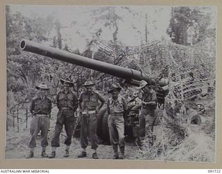 HAWAIN, WEWAK AREA, NEW GUINEA. 1945-05-09. CHAPLAIN J.J. DINEEN (1), AND MEMBERS OF A 2/3 FIELD REGIMENT GUN CREW ALONGSIDE A "LONG TOM" 155MM GUN. THE WEAPON IS BEING USED TO SUPPORT THE ATTACK ..