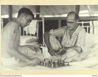 EGGY'S CORNER, PORT MORESBY AREA, PAPUA, 1944-02-19. NX140673 LIEUTENANT K.A. PEDDLE (1) OF THE 22ND INFANTRY BATTALION, PLAYING CHESS WITH NX163949 LIEUTENANT COLONEL E. TAYLOR, MBE, OF AUSTRALIAN ..