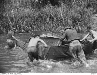 BOUGAINVILLE. 1945-05-21. PERSONNEL OF 58/59 INFANTRY BATTALION FERRYING A TRAILER LOADED WITH AMMUNITION FOR 2/4 ARMOURED REGIMENT MATILDA TANKS, SUPPORTING THE BATTALION ADVANCE SOUTH OF THE ..