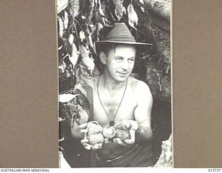 1943-09-15. NEW GUINEA. HODGES KNOLL. AFTER THE JAPANESE HAD BEEN DRIVEN FROM THIS FOX HOLE AT HODGES KNOLL NEAR KOMIATUM PTE. FRED GEE, OF TAMWORTH, N.S.W., FOUND THESE JAPANESE GRENADES. ..