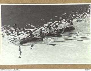 KUBA LAKE, RAMU VALLEY, NEW GUINEA. 1943-12-25. COMPETITORS PADDLING THEIR HOME-MADE RACING CRAFT, HEWN FROM A LOG, MOVING UP FOR THE START OF THE BOAT RACE AT THE CHRISTMAS CARNIVAL AND REGATTA ..