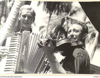 MILILAT, NEW GUINEA. 1944-08-23. VX147856 CORPORAL L. SMITH, VIOLINIST (1) AND TX14939 CORPORAL E.S.T. SAUNDERS, PIANO ACCORDIONIST (2) OF THE "TASMANIACS" THE TASMANIAN LINES OF COMMUNICATION ..