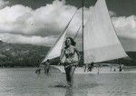 A young Tahitian woman in front of a outrigger canoe, Moorea