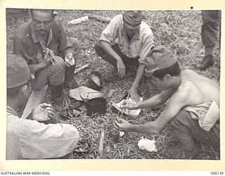 MUSCHU ISLAND, NEW GUINEA. 1945-09-11. GROUP OF JAPANESE OFFICERS HAVING THEIR MID-DAY MEAL, EATING WITH CHOPSTICKS. THEY SUPPLEMENTED THEIR OWN RATIONS WITH A TIN OF BULLY BEEF. THE ISLAND IS NOW ..