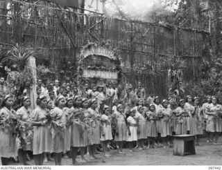 RAMALE VALLEY, NEW BRITAIN. 1945-10-02. NATIVES IN A TABLEAU ON THE STAGE SING "RAMALE GREETS YOU" AT THE CONCERT STAGED AS THANKSGIVING FOR LIBERATION BY THE RAMALE MISSION. PERSONNEL OF 11 ..